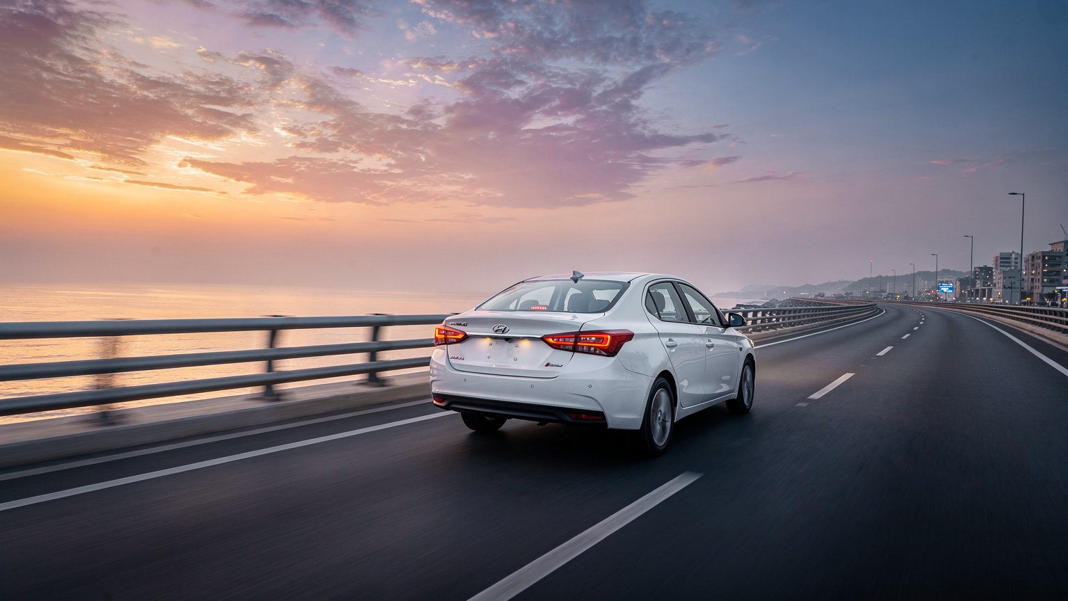 White sedan on a coastal expressway at dusk (illustrative image)