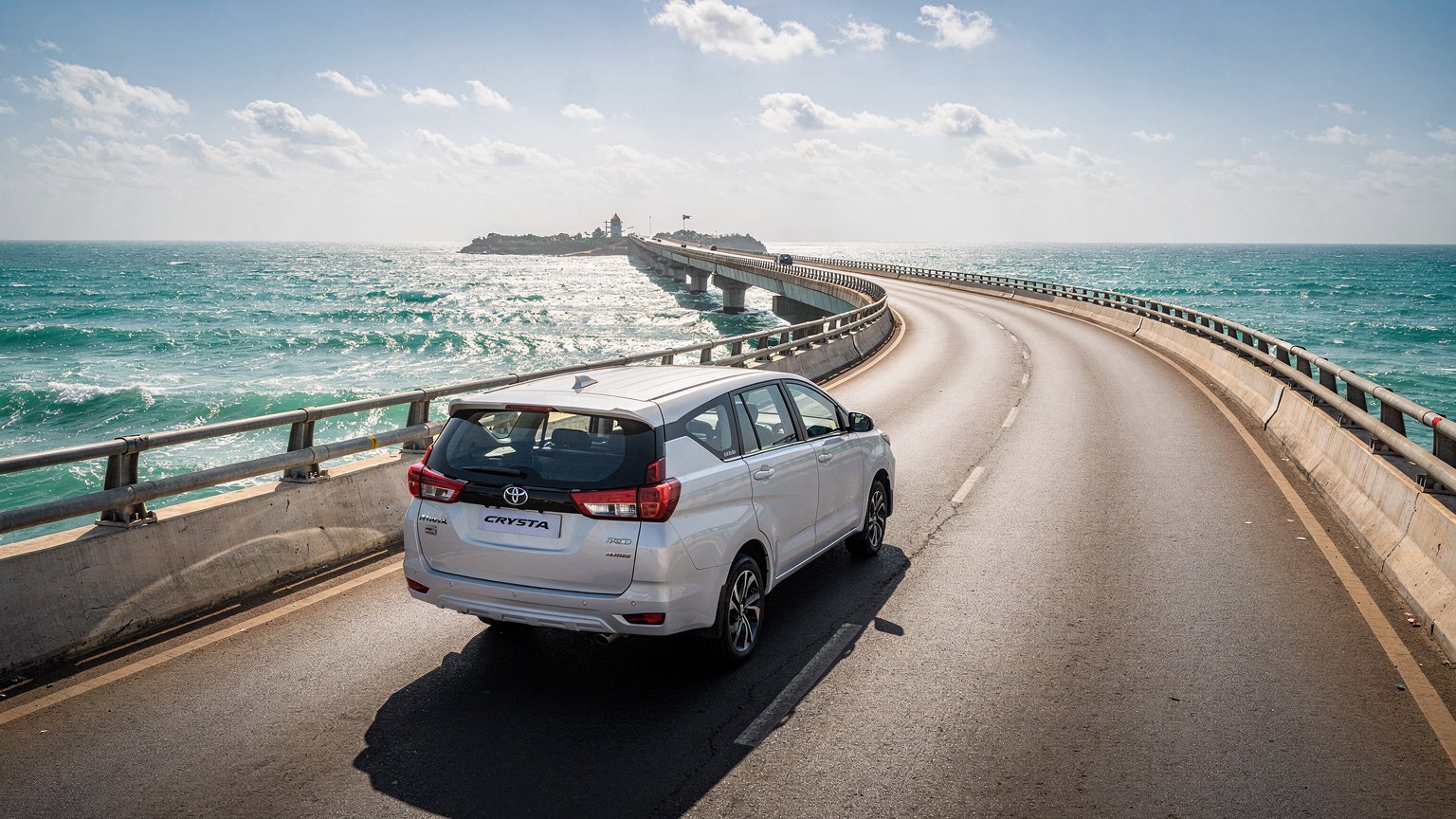White MPV taxi crossing a long sea bridge over blue water in coastal Tamil Nadu (illustrative image)