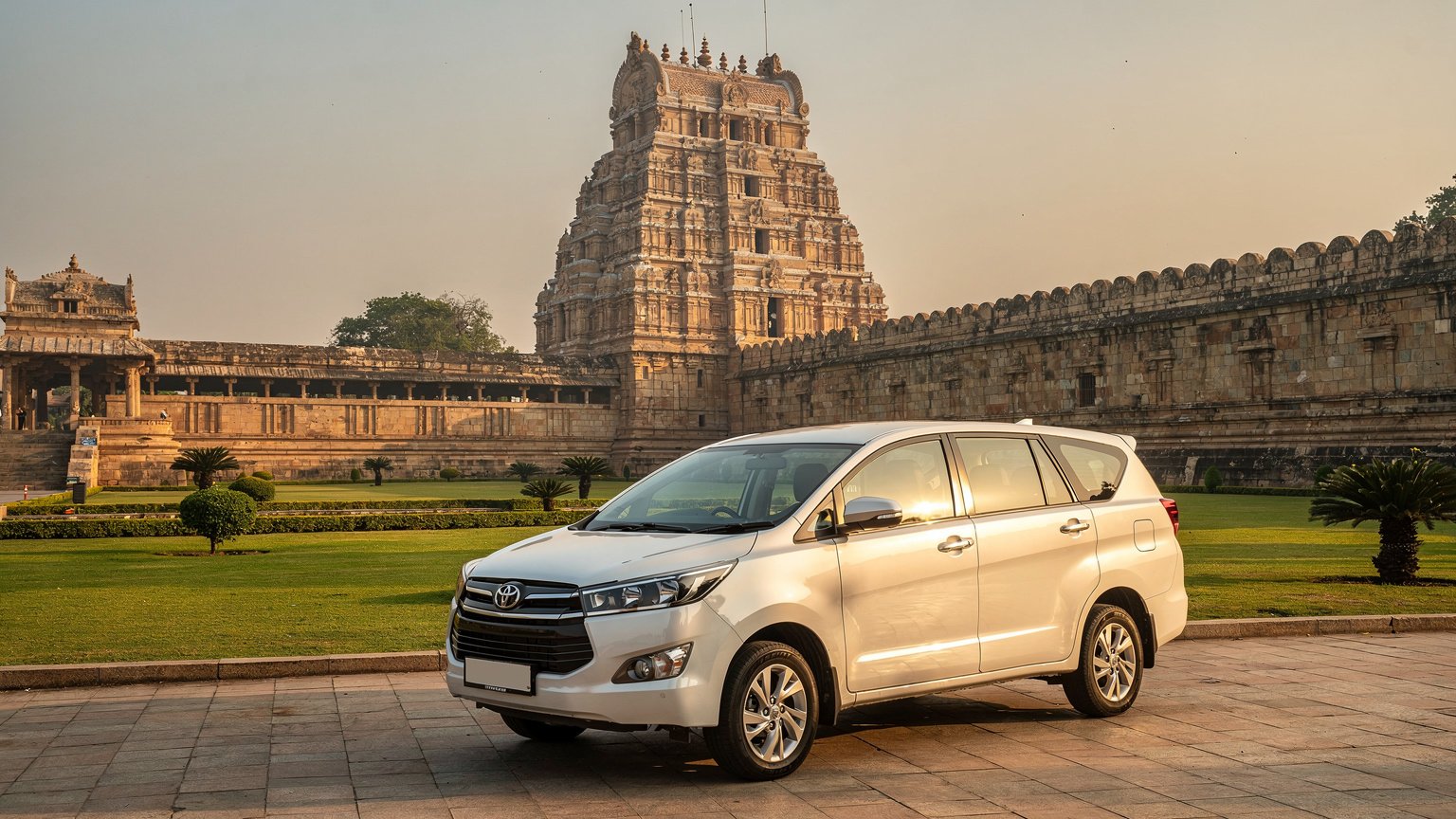 White MPV taxi near a large granite Chola-style temple (illustrative image)
