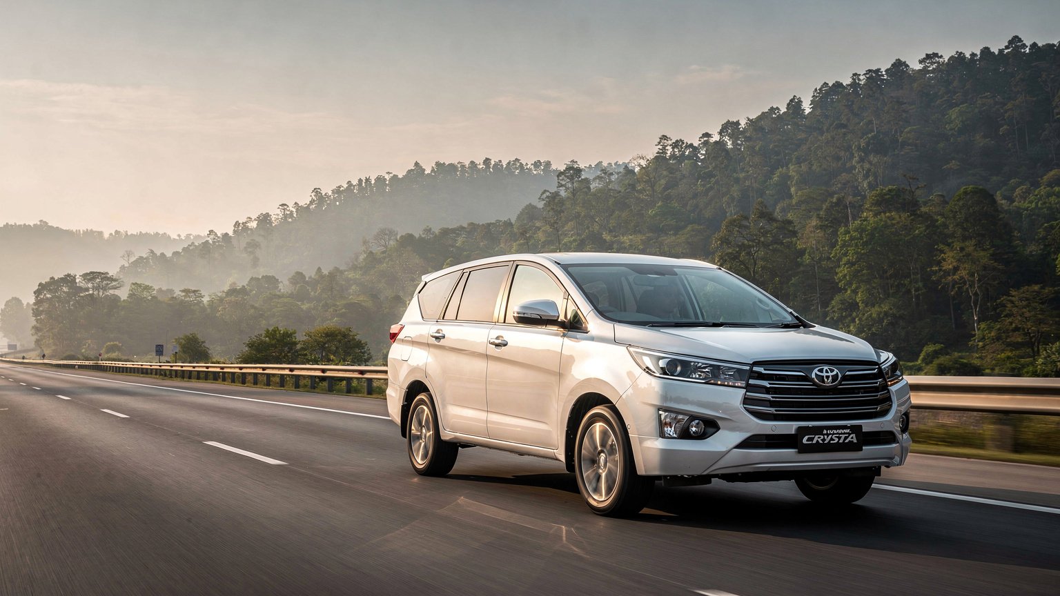 White MPV taxi on a highway toward forested hills (illustrative image)