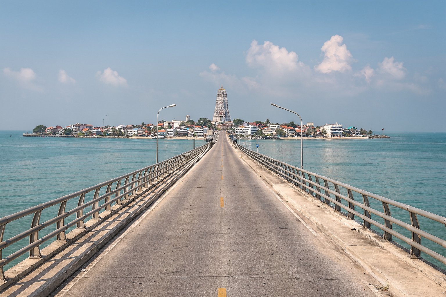 Road bridge over turquoise sea toward a coastal temple town (illustrative image)
